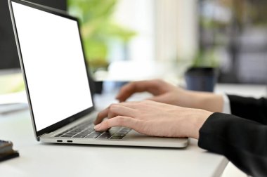 Side view image of a businesswoman typing on laptop keyboard, surfing the internet, using laptop computer at her office desk. cropped image