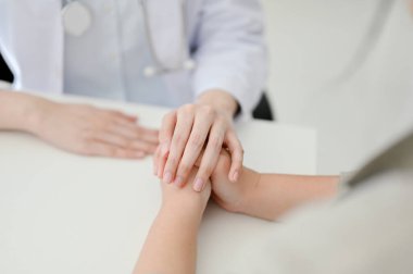 Close-up image of a caring female doctor holding a patient's hands to reassure and comfort her during the meeting.