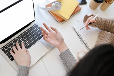 Top view of two creative and professional Asian female graphic designers working together in the office, discussing and brainstorming on their project. laptop white screen mockup
