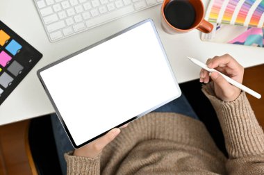 Top view of a female graphic designer designing her graphic artwork on digital tablet at her desk. tablet white screen mockup for display your graphic