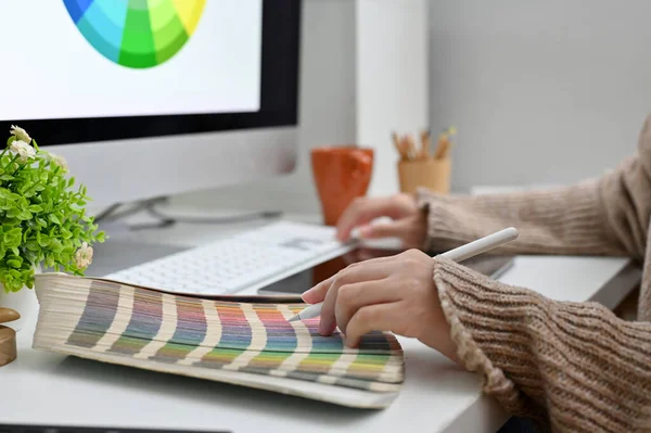 Side view of a female graphic designer working at her modern office desk, designing and choosing her product color template from color palette.