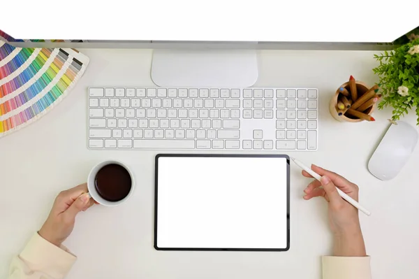 Minimal white workspace top view with a female graphic designer sipping morning coffee and using digital tablet. tablet white screen mockup