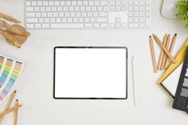 Top view of a minimal white graphic designer or editor workspace with digital tablet white screen mockup, color chart, color pencils, keyboard and stationery. 
