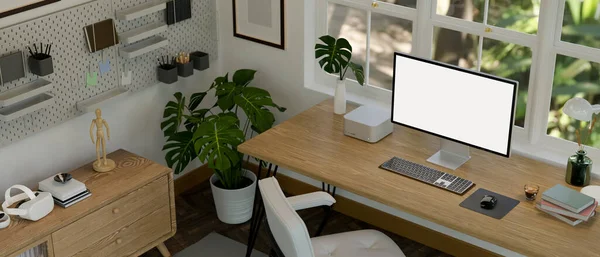 Top view of a minimal white home office interior with PC computer mockup and accessories on wood table against the window, wood cabinet, indoor plants, pegboard and decor. 3d render, 3d illustration