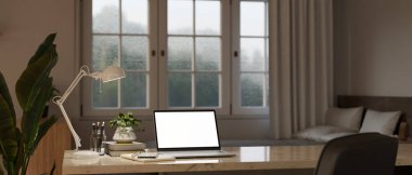 Comfortable home workspace in bedroom interior design with laptop white screen mockup, stationery, table lamp and decor on tabletop. 3d render, 3d illustration