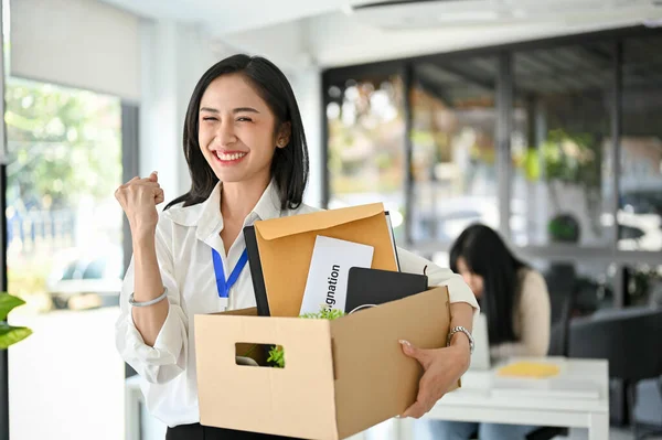 年轻的亚洲女办公室职员笑着 兴奋地庆祝着她的辞职 拿着她的个人物品 高兴地离开工作或换工作 — 图库照片