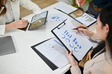 Profesyonel Asyalı iş kadını ya da kadın finans analistinin yakın plan görüntüsü toplantıda ekibiyle birlikte mali verileri gözden geçiriyor..