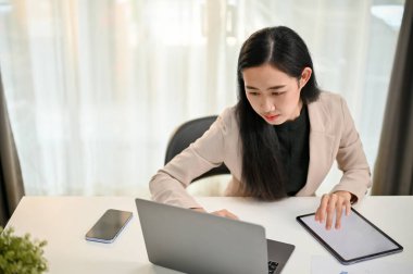 Profesyonel Asyalı iş kadını laptoptaki işine odaklanıyor, ofisteki masasında dizüstü bilgisayar kullanıyor..