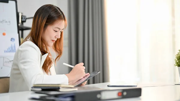 디지털 태블릿을 사용하여 사무실에 그녀의 책상에서 일하는 아시아 사업가의 매력적 — 스톡 사진