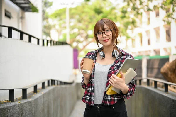 キャンパスの建物の外を歩いている間に彼女のテイクアウトコーヒーカップ ラップトップ 学校の本を保持カジュアル服の魅力的でかなり若いアジアの女性大学生 — ストック写真