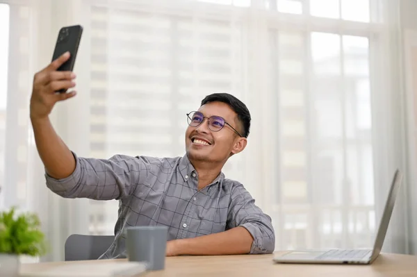 面带微笑的千年亚洲男人或商人 坐在写字台前拿着手机自私自利 — 图库照片