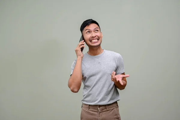 穿着休闲装的快乐而又笑着的亚洲男人在电话里与人交谈 与人交易或谈论着什么 站在一个绿色工作室的背景下 — 图库照片