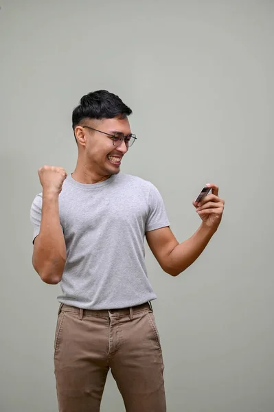 Heureux Excité Homme Asiatique Millénaire Vêtements Décontractés Tenant Son Téléphone — Photo