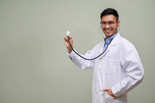 Profesjonalny Uśmiechnięty Milenijny Azjatycki Lekarz Białym Płaszczu Trzyma Swój Stetoskop — Zdjęcie stockowe