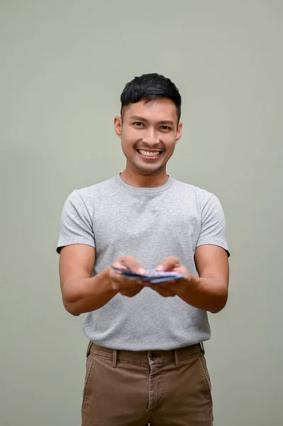 Feliz Sonriente Hombre Asiático Milenario Con Ropa Causal Entregando Dinero —  Fotos de Stock