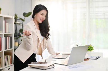 Profesyonel Asyalı iş kadını ya da kadın CEO 'su ekibiyle çevrimiçi bir toplantı yaparken masaya yaslanıyor ve özel ofisinde çalışıyor..