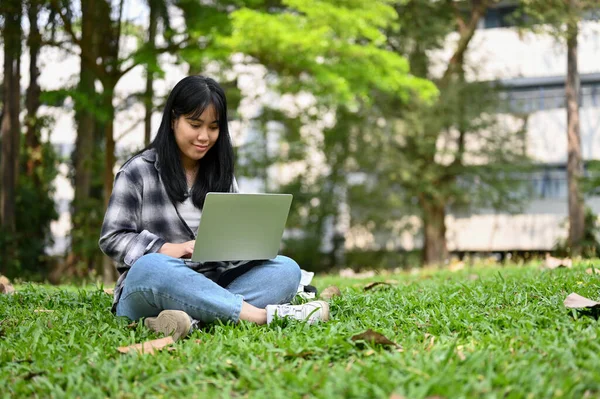 迷人的年轻亚洲女大学生在网站上搜索信息 做在线作业 在校园公园里使用笔记本电脑 — 图库照片