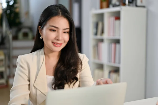 漂亮迷人的千年亚洲女商人或女老板看着笔记本电脑屏幕 在办公室里为她的笔记本电脑项目工作 — 图库照片