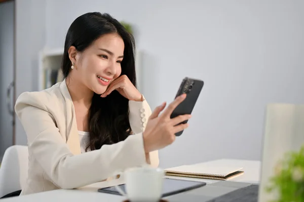 Krásná Tisíciletá Asijská Podnikatelka Ruku Bradě Při Pohledu Displej Telefonu — Stock fotografie