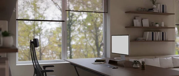 現代的なホームオフィスのワークスペースのインテリアデザインは コンピュータのブランクスクリーンモックアップと窓の近くの広葉樹テーブル上のアクセサリーと 3Dレンダリング 3Dイラスト — ストック写真