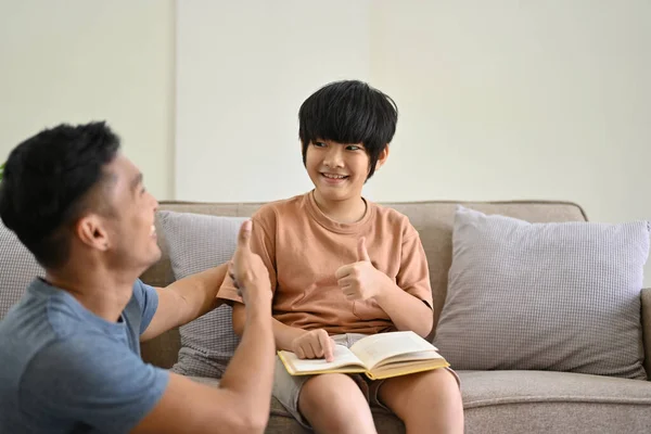 귀엽고 즐거운 아시아 소년은 엄지손가락을 집에서 시간을 보내면서 아버지와 이야기하는 — 스톡 사진