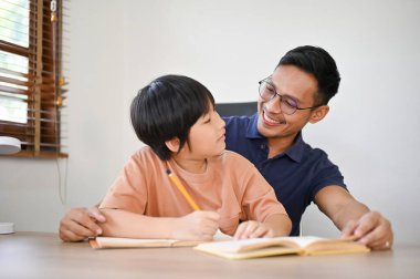 Kafası karışmış ve meraklı küçük oğlu bir soru soruyor. Babası ona ders veriyor ve ödevlerini yapmasına yardım ediyor..