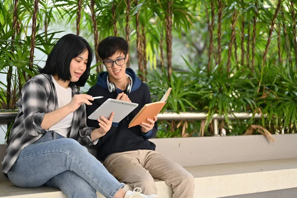 聪明的年轻亚洲女大学生一起坐在校园大楼里 一边和她的男性朋友聊天一边教数学 — 图库照片