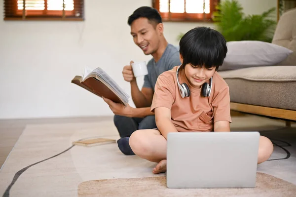 Bonito Ásia Jovem Menino Usando Laptop Enquanto Seu Pai Livro — Fotografia de Stock