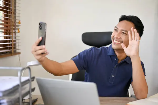 快乐快乐的千年亚洲商人坐在办公室的办公桌前 和他的女朋友打了一个视频电话 — 图库照片