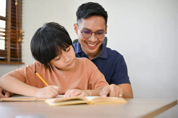 Ystävällinen Huolehtiva Aasialainen Isä Opettaa Auttaa Poikaansa Tekemään Kotitehtäviä Opiskelemaan — kuvapankkivalokuva
