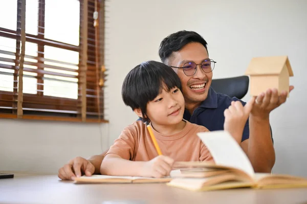 친절하고 아시아인 아버지는 아들에게 숙제를 하거나 종이에 모형을 그리는 가르친다 — 스톡 사진