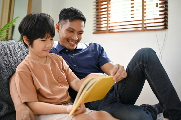 기쁨에 행복해 아시아인 아버지는 거실에서 편안하게 쉬면서 읽거나 아들에게 이야기해 — 스톡 사진