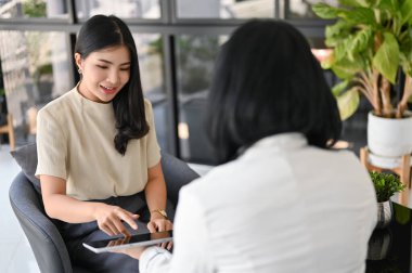 Güzel ve mutlu Asyalı bayan patron asistanıyla konuşuyor ya da çalışanıyla ofisinde gayri resmi bir görüşme yapıyor..