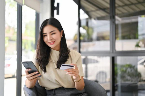 迷人的千年亚洲女性 手持智能手机和信用卡 使用移动银行应用软件或网上购物应用软件 — 图库照片