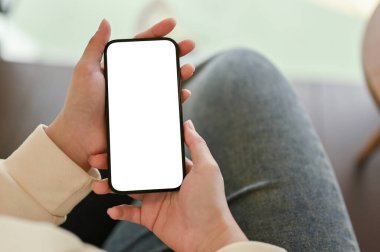Kanepede dinlenen ve akıllı telefonunu kullanan bir kadın akıllı telefonun beyaz ekran modelini bir kadının ellerinde yakın plan görüntüsü..