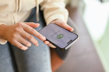 Chiang Mai, Tayland - 31 Mart 2023: Akıllı telefonunda WhatsApp uygulamasını kullanan günlük kıyafetli bir kadın. Ekranda WhatsApp logosu olan iPhone. 