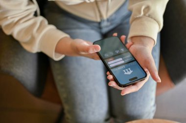 Chiang Mai, Tayland - 31 Mart 2023: Çevrimiçi mobil bankacılık uygulaması kullanan günlük kıyafetler giyen bir kadın. Ekranda online bankacılık logosu olan iPhone.