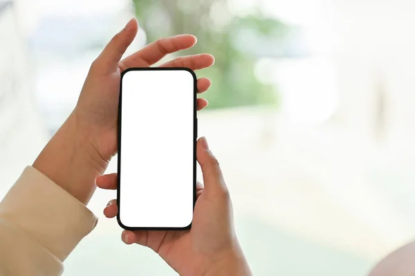 スマートフォンの白いスクリーンモックアップを持っている女性の手のクローズアップ画像は ぼやけた明るい背景の上に画面にあなたのグラフィック広告を表示する — ストック写真