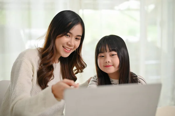 친절하고 아시아인 자매가 여동생을 집에서 노트북으로 온라인 스터디 수업을 들었습니다 — 스톡 사진