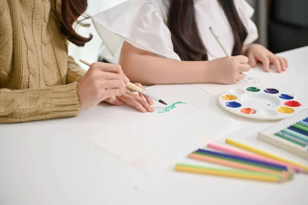 彼女の小さな娘に家で水の色で絵を描くと色を教える介護アジアのお母さんのクローズアップイメージ — ストック写真