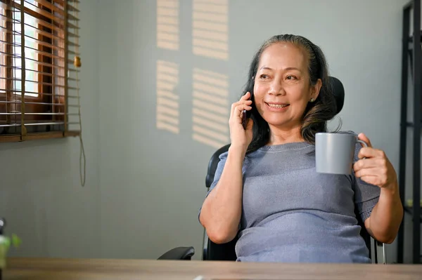 Šťastná Uvolněná Asijská Podnikatelka Hovořící Telefonu Popíjející Kávu Stolem — Stock fotografie