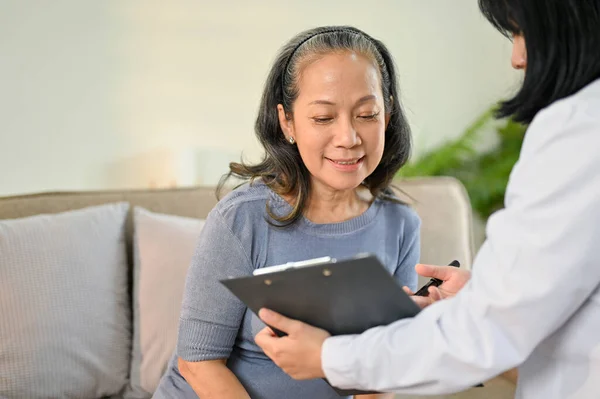 stock image Beautiful and happy senior Asian woman is discussing her medical treatment plan with a doctor in the examination room at a hospital. Health care concept