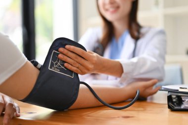 Hastanın nabzını, kalp atışlarını ve tansiyonunu muayene odasında monitörle kontrol eden Asyalı bir kadın doktorun yakın görüntüsü. Tıbbi ve sağlık hizmetleri kavramı