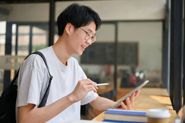 잘생긴 아시아 대학생 자신의 디지탈 태블릿을 사용하여 프로젝트를 진행하며 커피숍에 — 스톡 사진