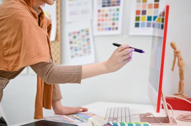 Stüdyosunda çalışan yetenekli bir kadın grafik tasarımcısının yakın plan görüntüsü bilgisayar ekranında stil kalemi gösteriyor..