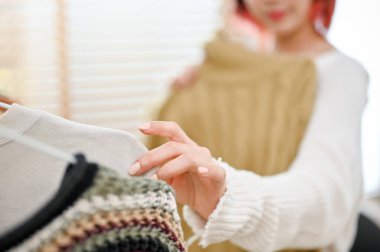 Genç bir Asyalı kadın giyim mağazasının yakın plan büyücüsü yeni kıyafet koleksiyonunun kalitesini kontrol ediyor..