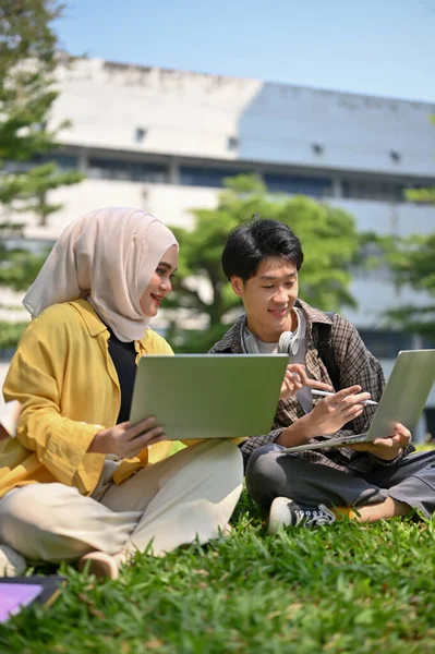 快乐的年轻的亚洲穆斯林女大学生与她的男性朋友分享她的想法和讨论她的工作 同时一起在校园公园放松一下 — 图库照片