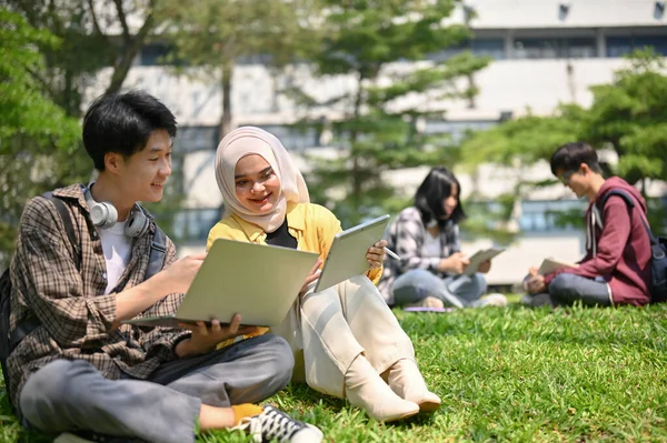 两个亚洲大学生坐在草地上 一起在校园公园里闲聊 一起学习功课 — 图库照片