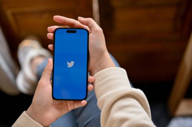 Chiang Mai, Tayland - 05 Nisan 2023: Twitter logolu iPhone tutan bir kadının üst görüntüsü. çevrimiçi topluluk, sosyal medya, uygulama