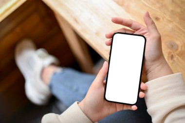 Bir kafede dinlenirken akıllı telefonunu kullanan sıradan giyinmiş bir kadının en iyi görüntüsü. Akıllı telefon beyaz ekran modeli. Teknoloji ve insanlar kavramı